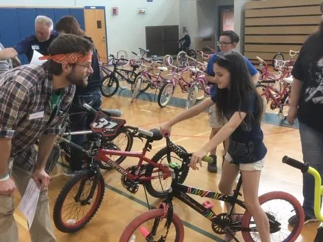 A volunteer fitting a girl to her new bike