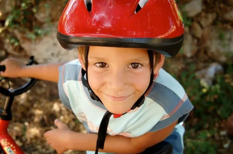 A smiling boy in a red bike helmet