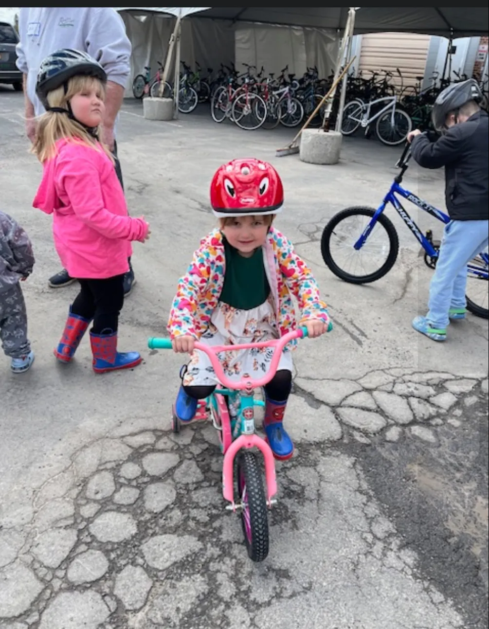 A little girl in a red helmet riding her new bike