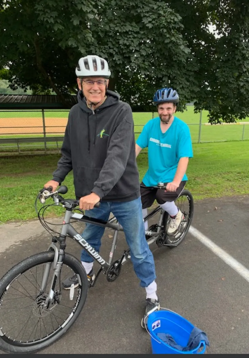 Two riders on a tandem bike in the park