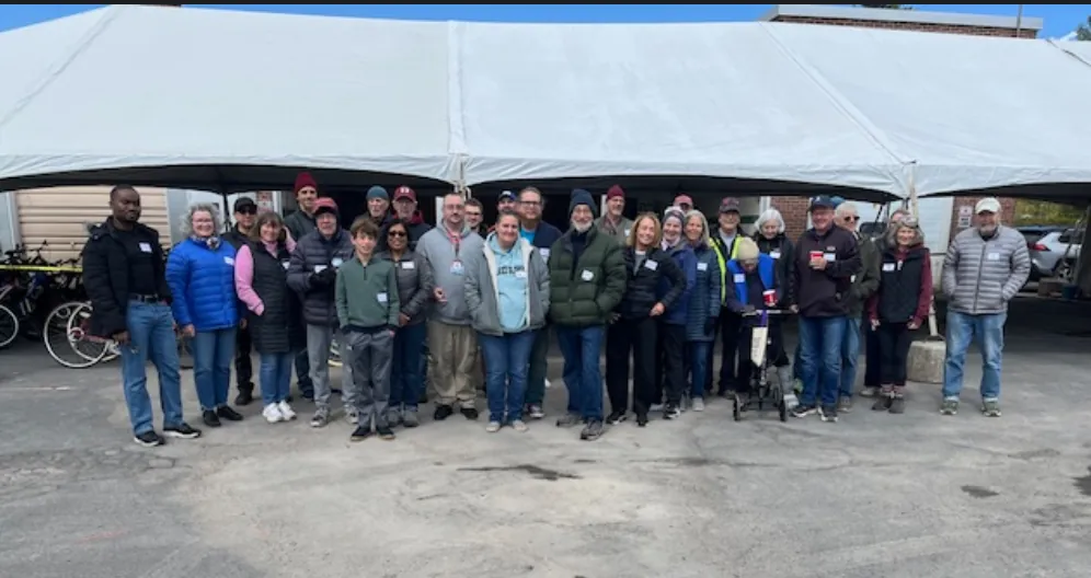 A large group of Community Bikes volunteers under a tent